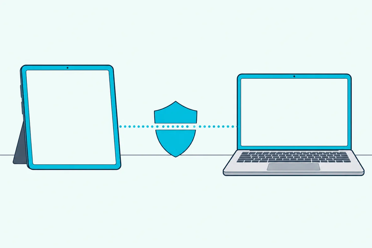 Tablet and laptop with a small teal shield standing between them on a desk