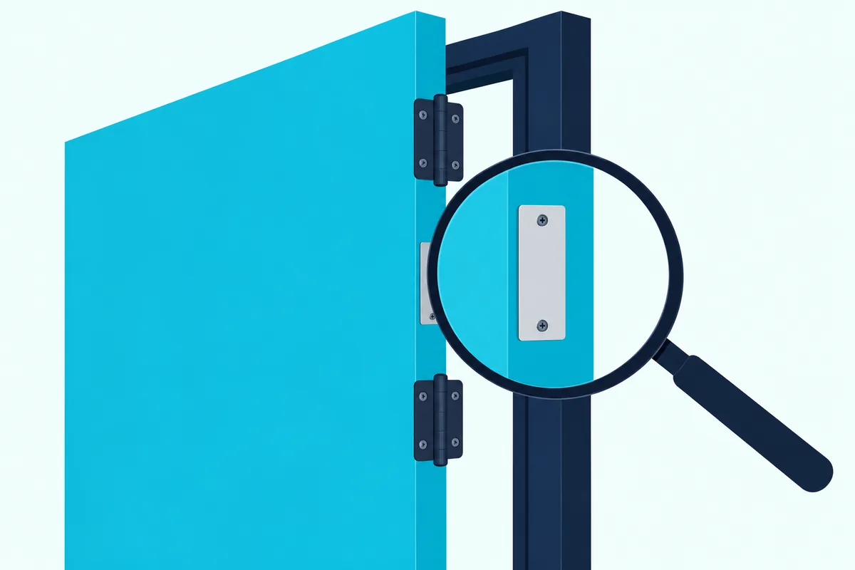 A blank metal label plate on the hinge edge of a fire door, seen through a magnifying glass