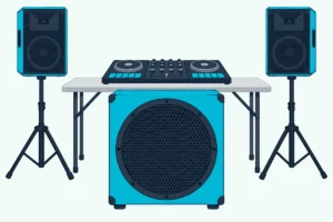 A DJ controller on a table between two speakers on stands, with a large subwoofer cabinet on the floor in front