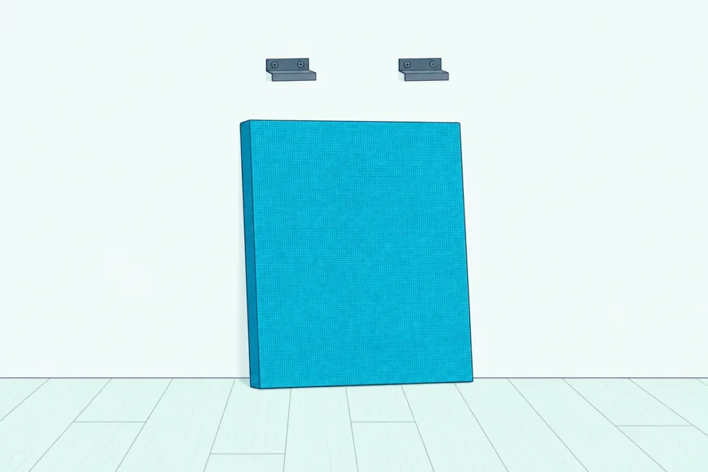 A fabric-wrapped acoustic panel resting on the floor against a wall, below the bare metal clips it hung on