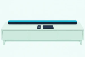 Soundbar on a low console with a small remote and a smartphone lying face down in front of it