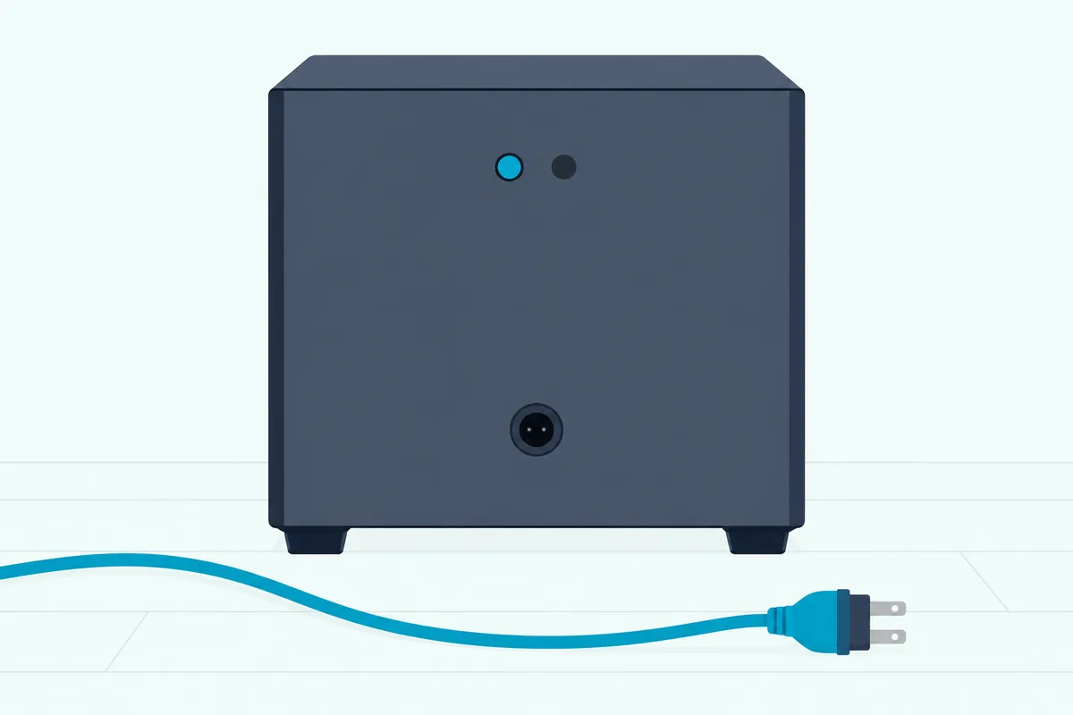 Back panel of a cube subwoofer with a small round button and indicator window, its power cord unplugged beside it