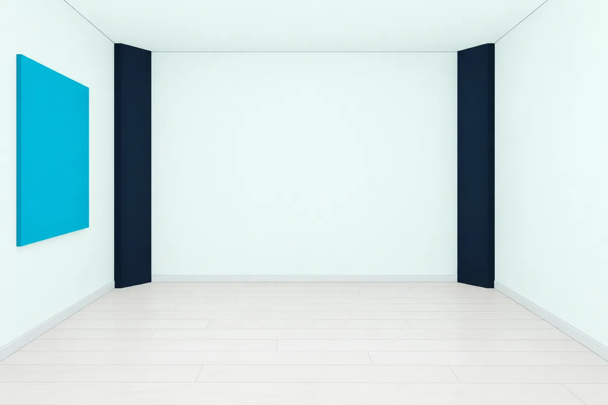 Tall triangular bass traps standing floor to ceiling in two corners of an empty room, with a flat panel on the side wall