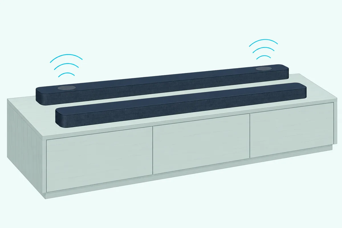 Two long dark soundbars side by side on a low wooden media cabinet, one with small round grilles on its top surface
